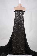 A mannequin wearing a long, black lace dress with a floral pattern.