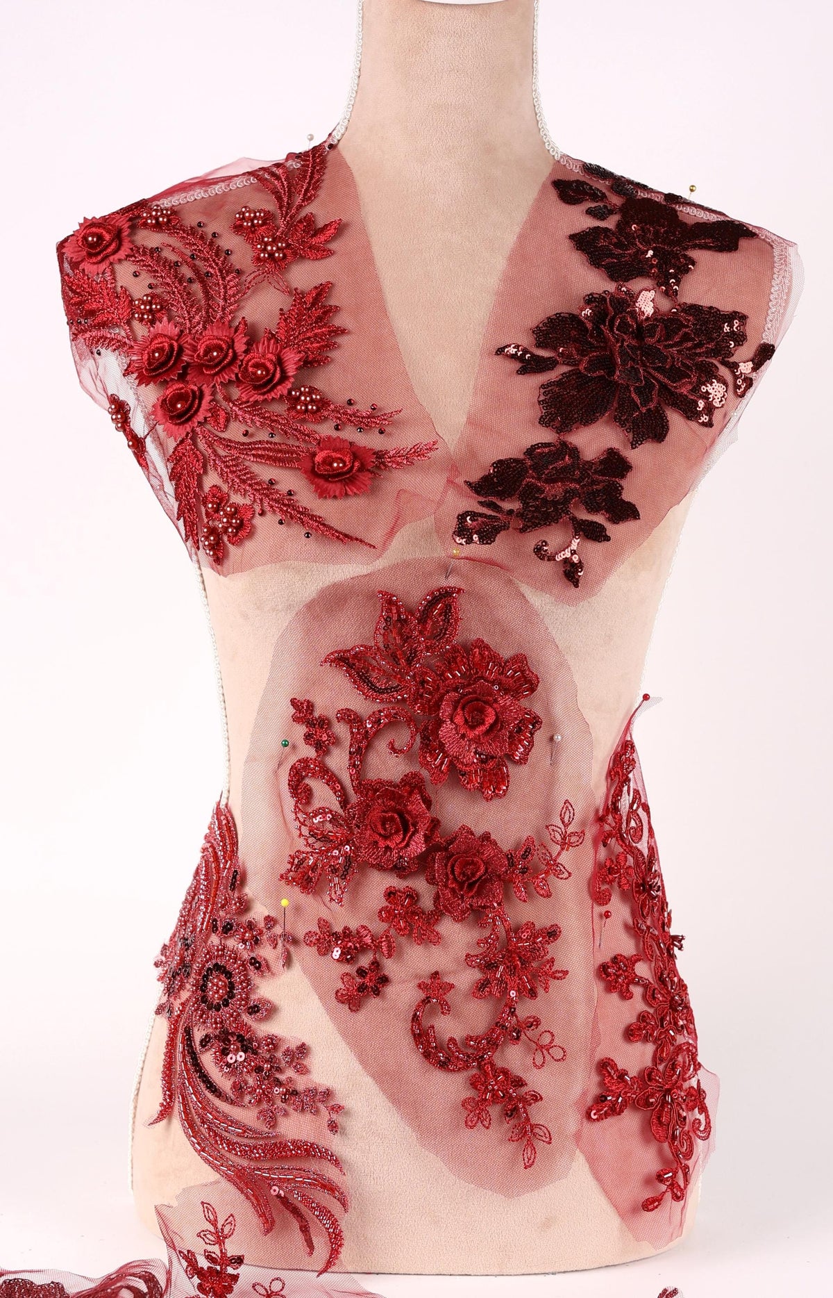 A mannequin wearing a red dress with intricate floral and lace patterns.