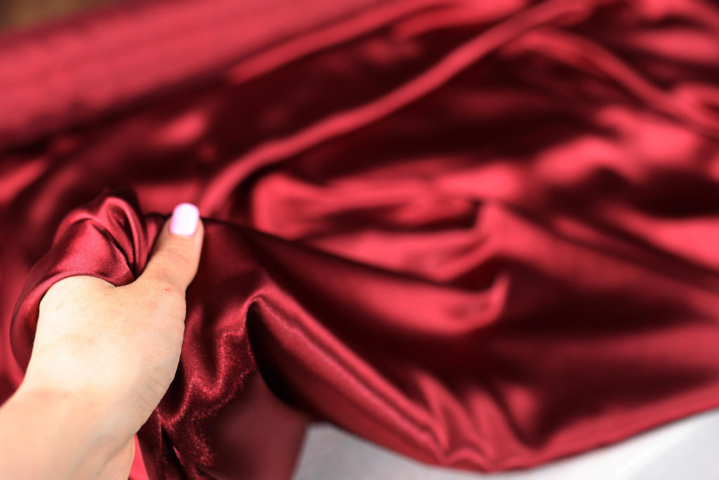 a person is holding a red satin material
