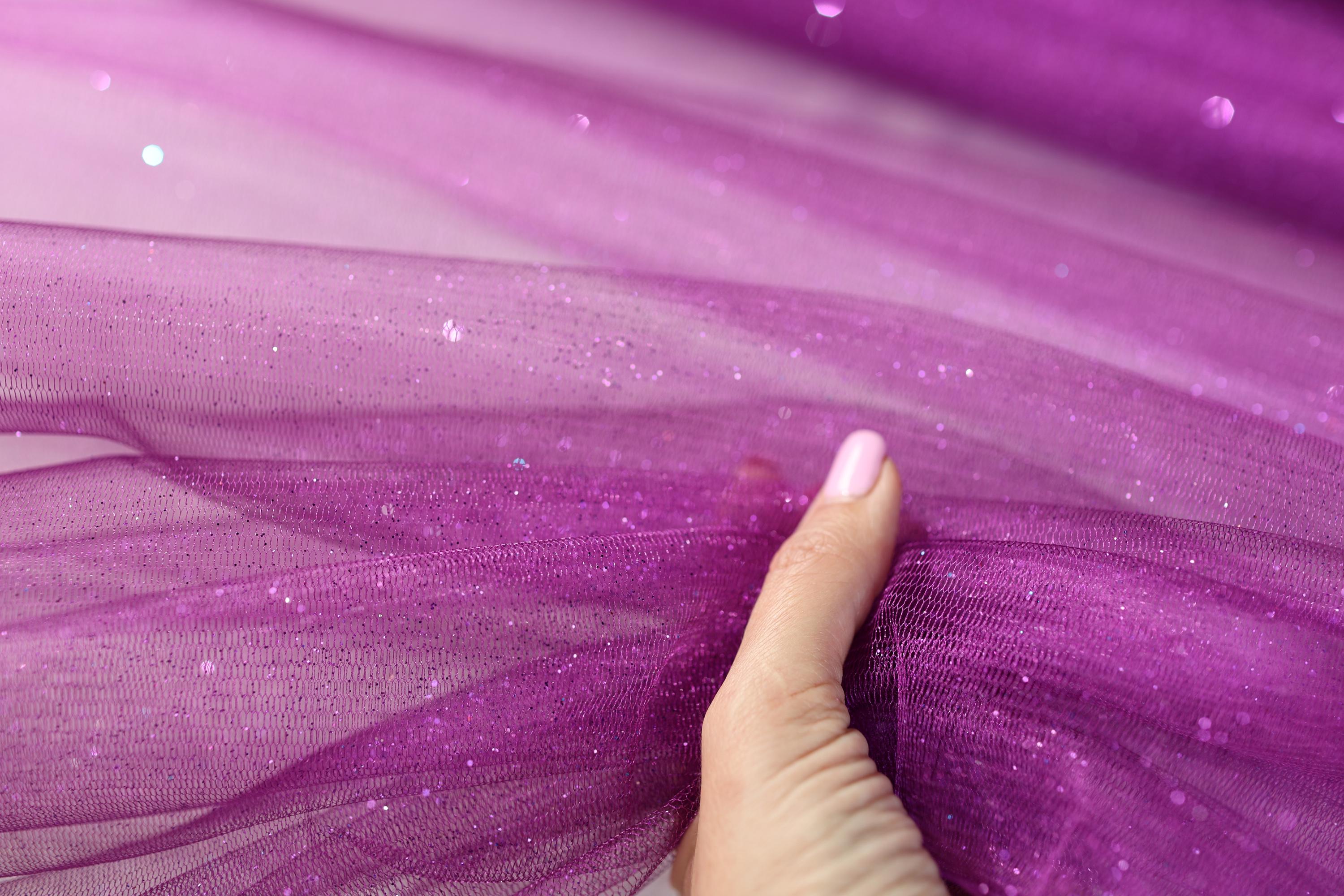 a woman's hand touching a purple tulle