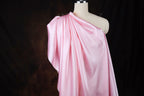 A mannequin wearing a pink satin dress with a draped, flowing silhouette.