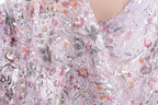 a close-up view of a delicate, intricately embroidered fabric with a floral pattern. The fabric appears to be made of sheer material, giving it a soft and delicate appearance. The embroidery features a variety of flowers and leaves in shades of pink, purple, and green, creating a visually appealing and detailed design.