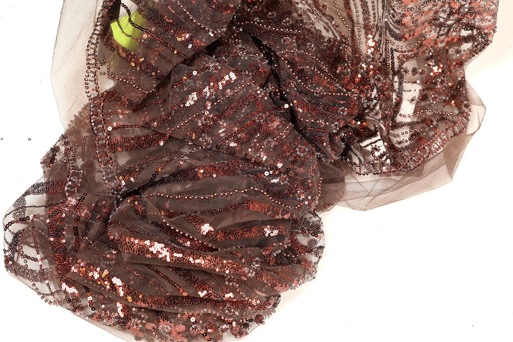 a close-up view of a piece of brown fabric with a sequined pattern, featuring a mix of brown and gold colors.