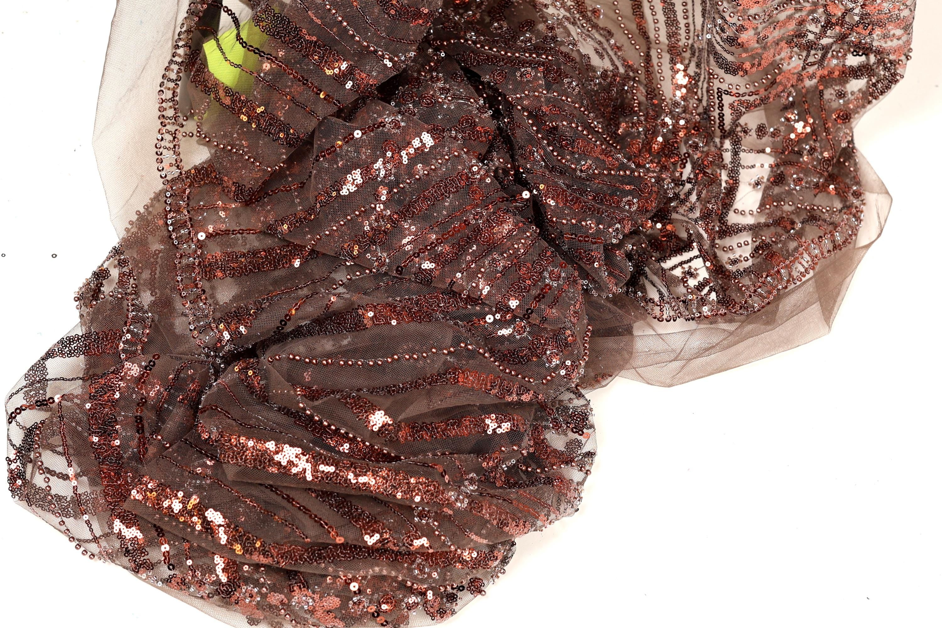 a close-up view of a piece of brown fabric with a sequined pattern, featuring a mix of brown and gold colors.