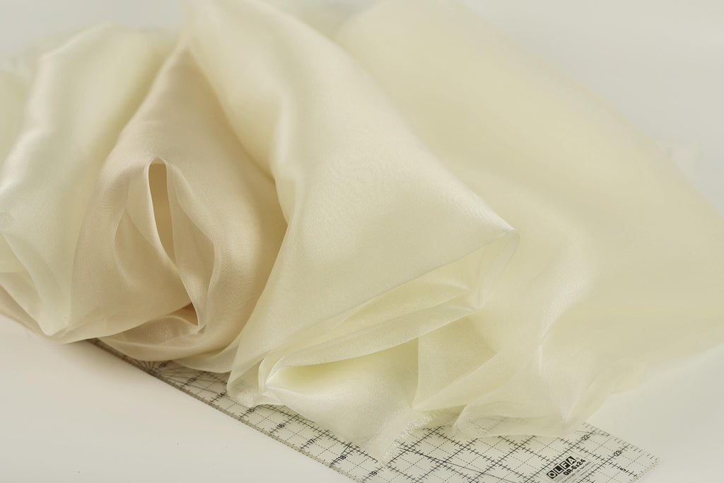 a close-up view of a piece of fabric, possibly silk or chiffon, with a ruler placed on top of it.