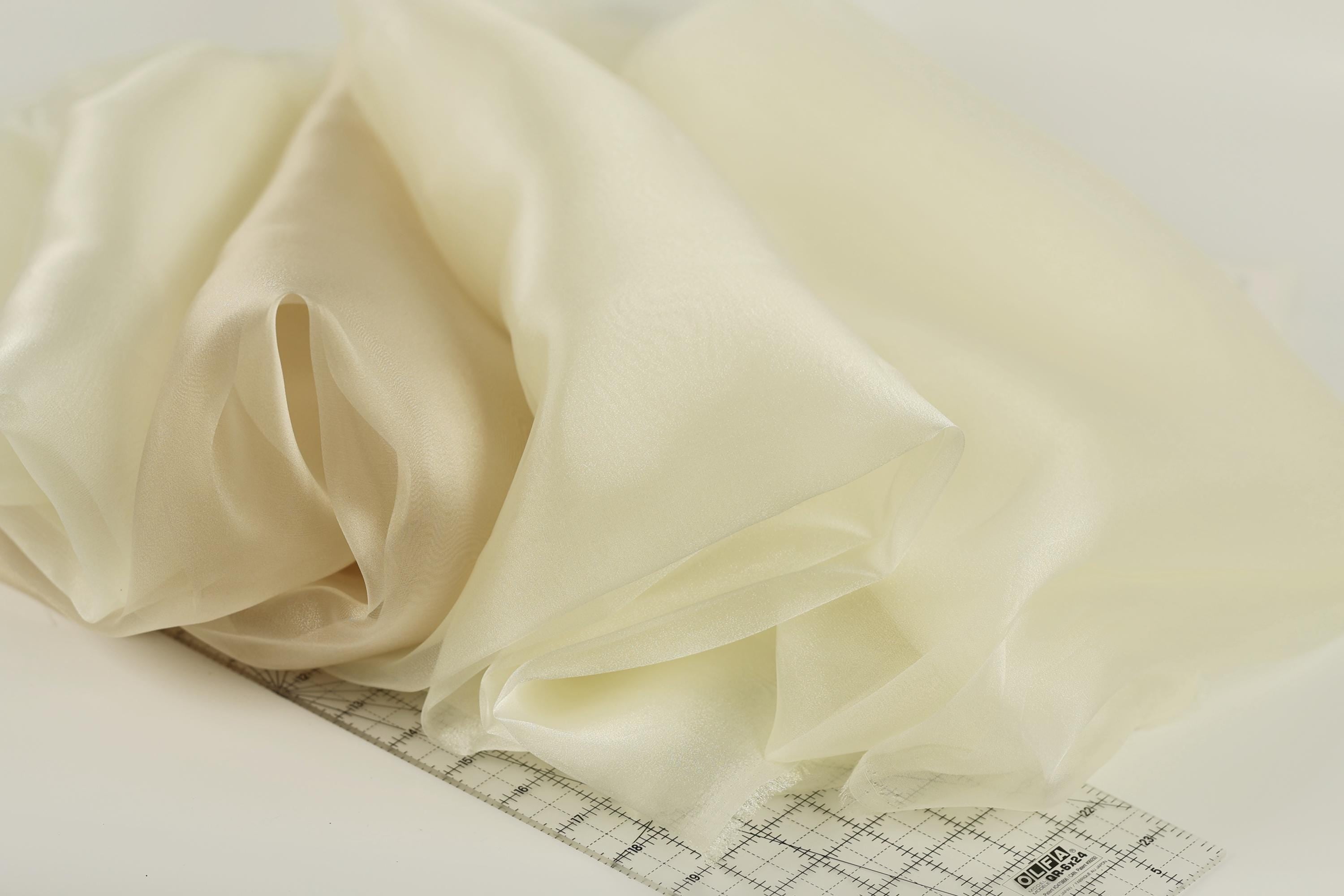a close-up view of a piece of fabric, possibly silk or chiffon, with a ruler placed on top of it.