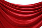 a close-up view of a red velvet fabric, with its folds and creases creating a textured and flowing appearance.