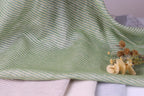 a close-up view of a green and white striped fabric, with a small bouquet of dried flowers resting on top of it.