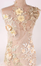 A mannequin torso covered in intricate, delicate embroidered floral designs in various shades of yellow and beige.