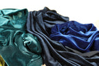 a close-up view of several pieces of fabric, including blue and green velvet-like materials, with a textured and wrinkled appearance.