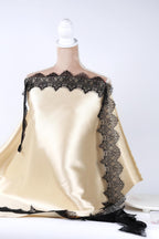 A mannequin wearing a beige satin dress with black lace trim, displayed against a white background.