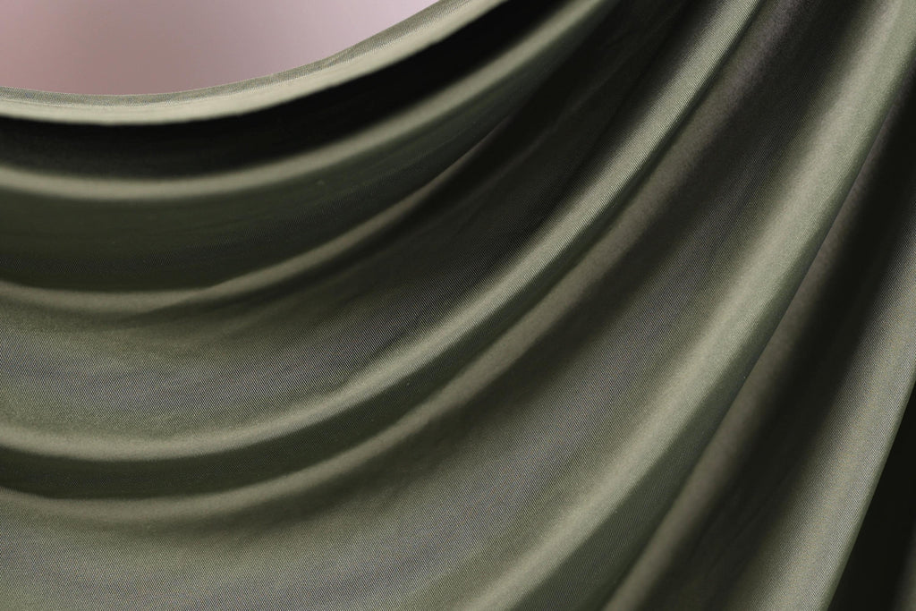 The image is a close-up of a green fabric, possibly a piece of clothing or a textile. The fabric has a smooth, flowing texture and appears to be made of a shiny, shiny material. The image does not contain any discernible objects or actions, and there are no specific details provided about the color or pattern of the fabric.