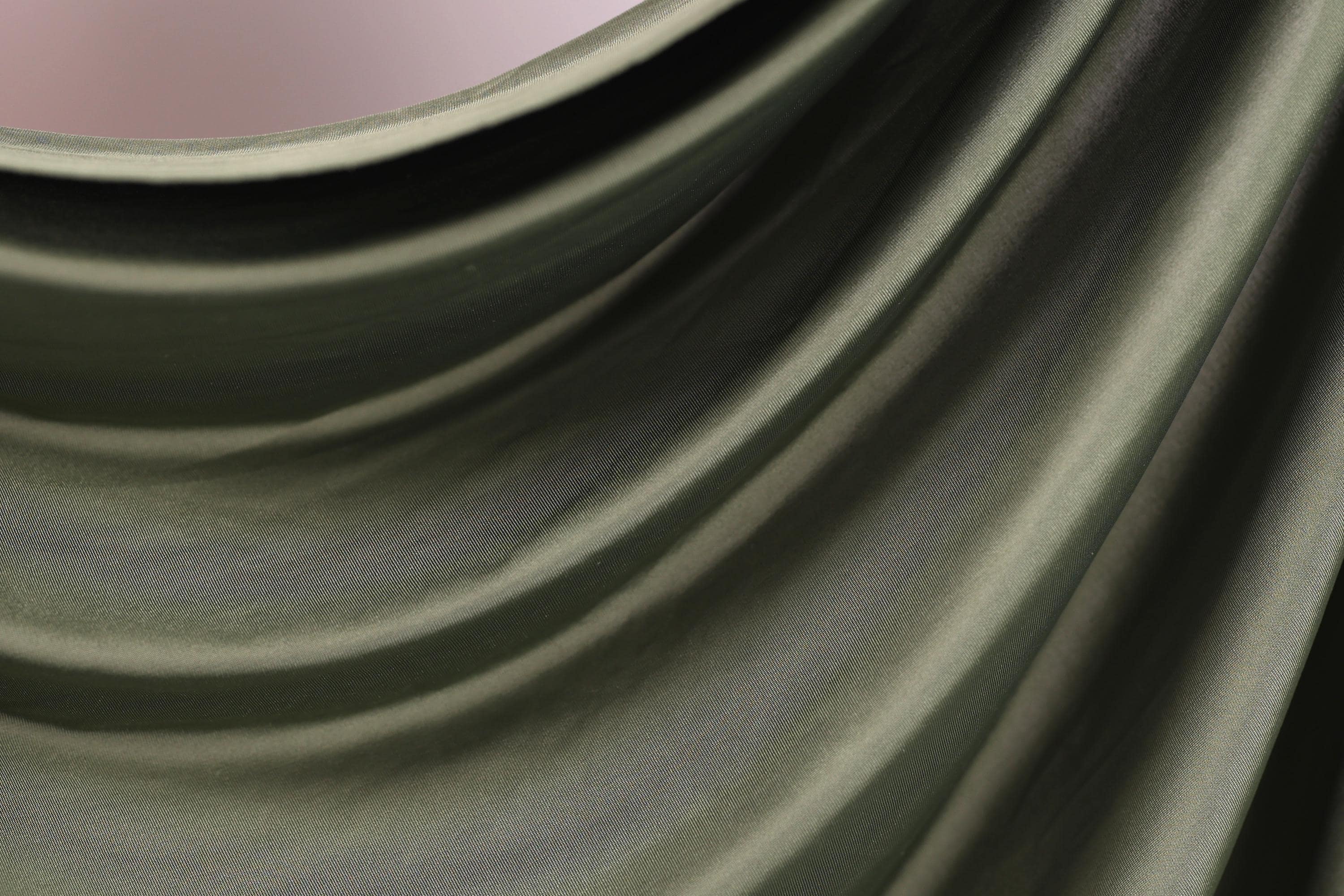 The image is a close-up of a green fabric, possibly a piece of clothing or a textile. The fabric has a smooth, flowing texture and appears to be made of a shiny, shiny material. The image does not contain any discernible objects or actions, and there are no specific details provided about the color or pattern of the fabric.