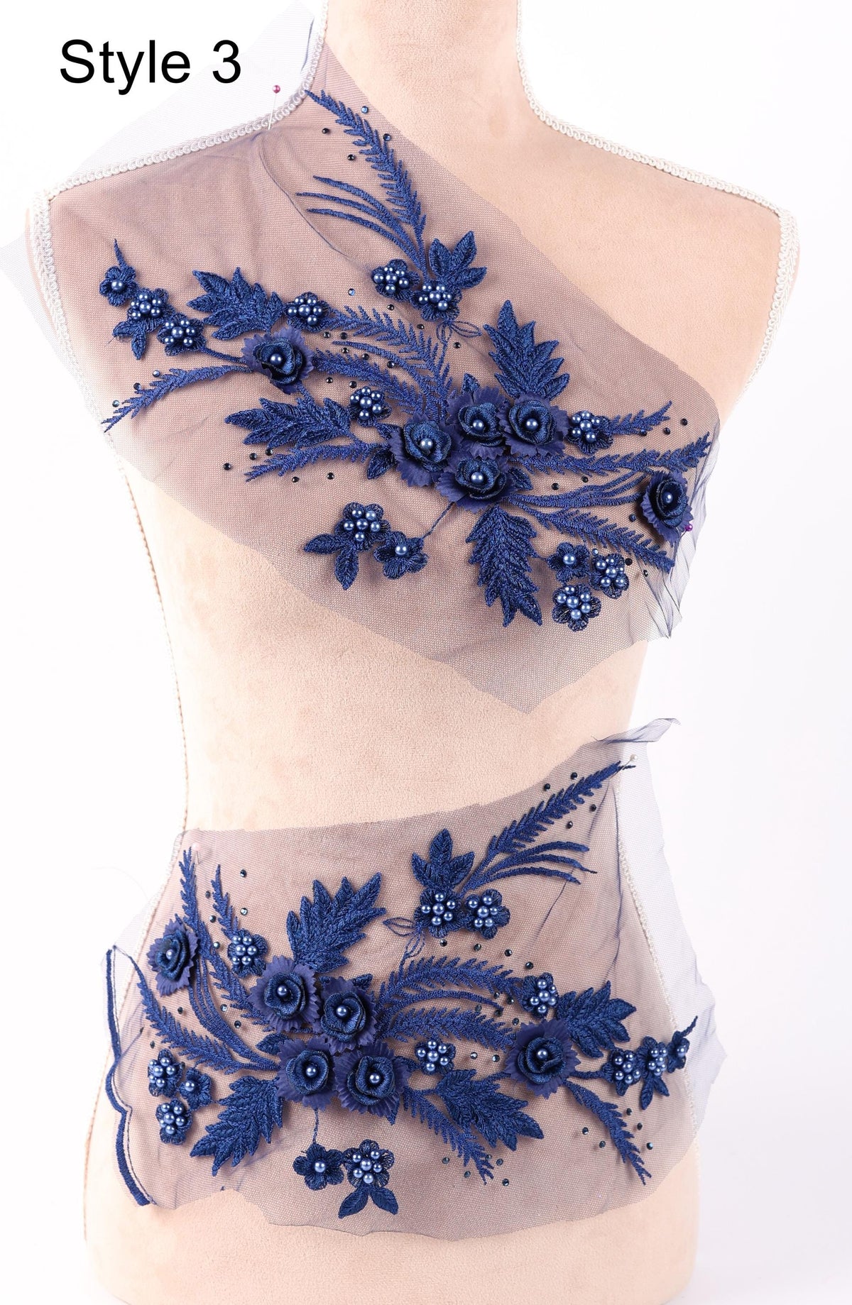 A mannequin wearing a dress with a floral pattern made of blue fabric and beads.