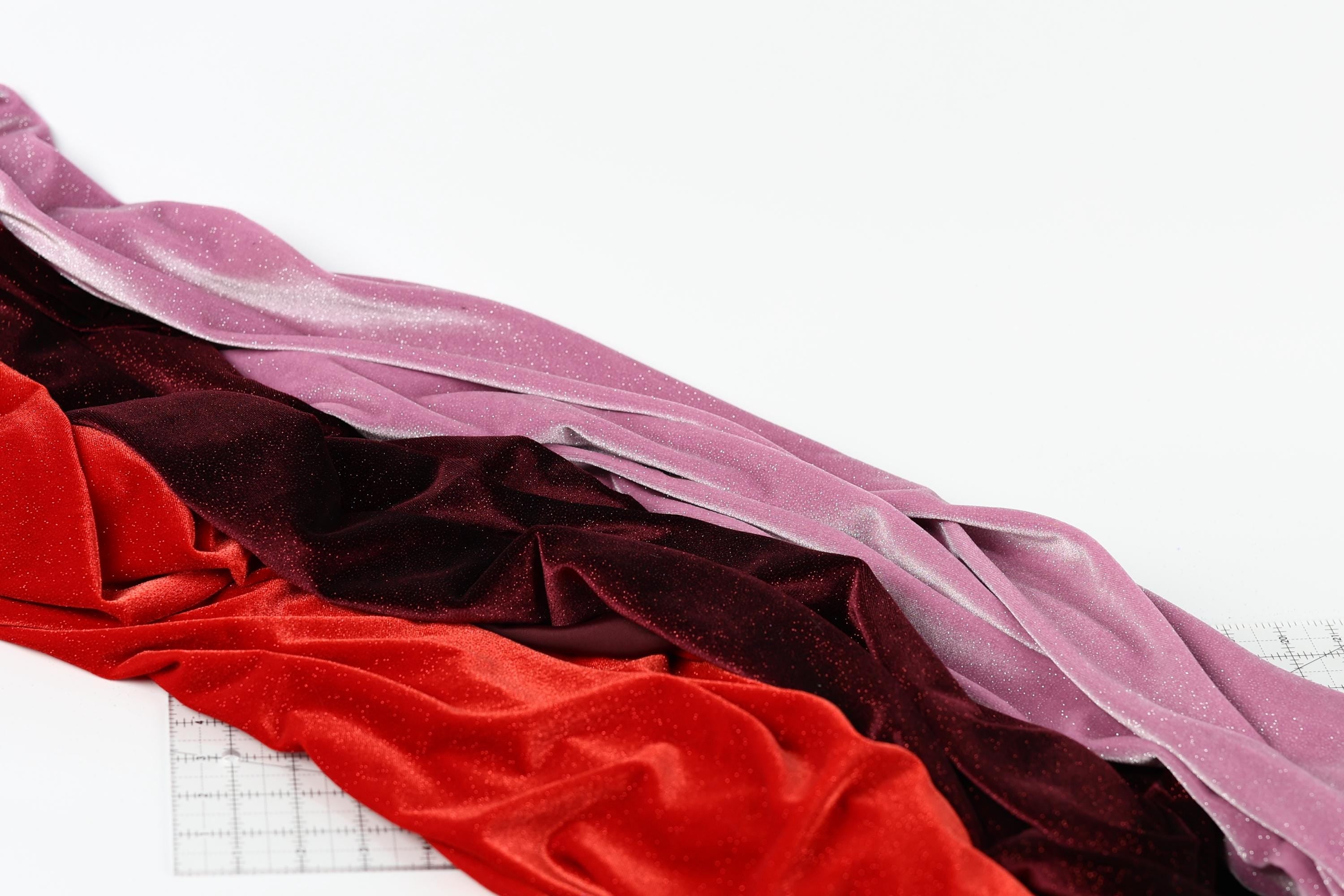 a variety of colorful fabrics, including red velvet, burgundy velvet, and pink velvet, arranged on a white background.
