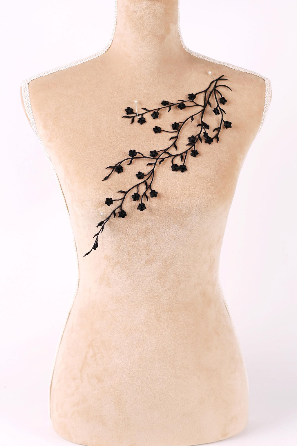 A mannequin with a beige body and a black branch-like design on its chest.