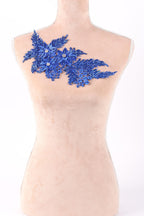 A mannequin torso with a decorative blue floral piece on it.