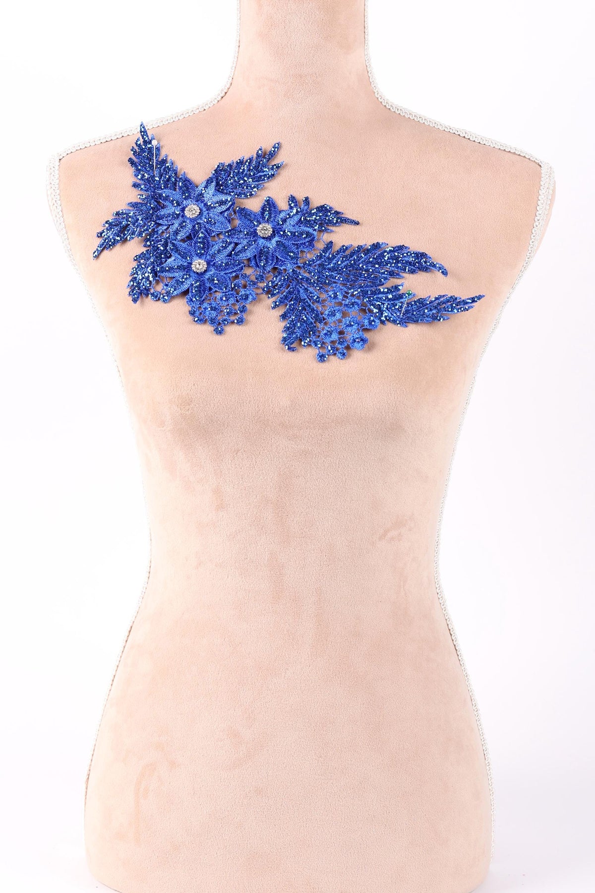A mannequin torso with a decorative blue floral piece on it.