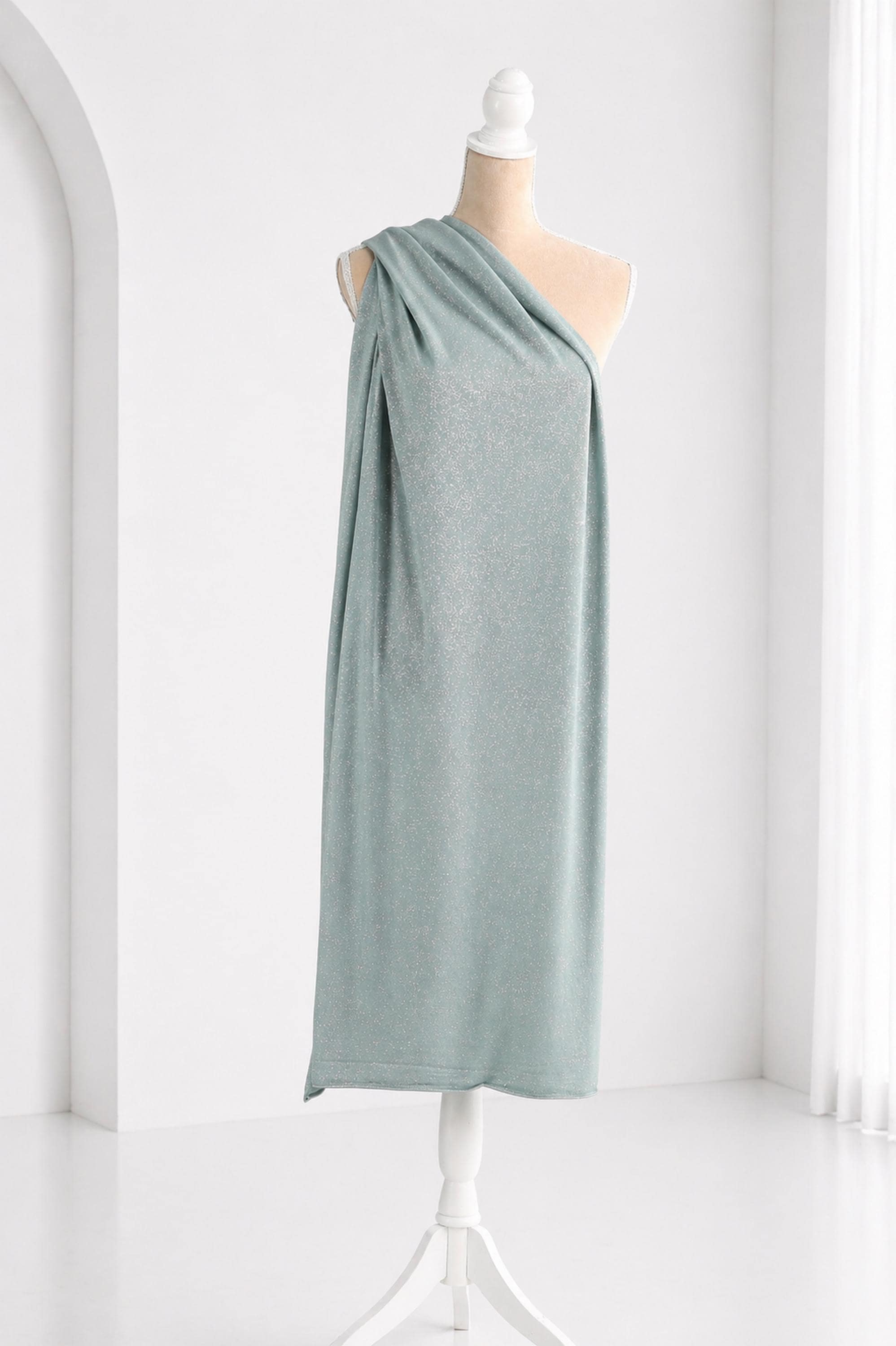 A mannequin wearing a light blue one-shoulder dress with a draped, flowing design.