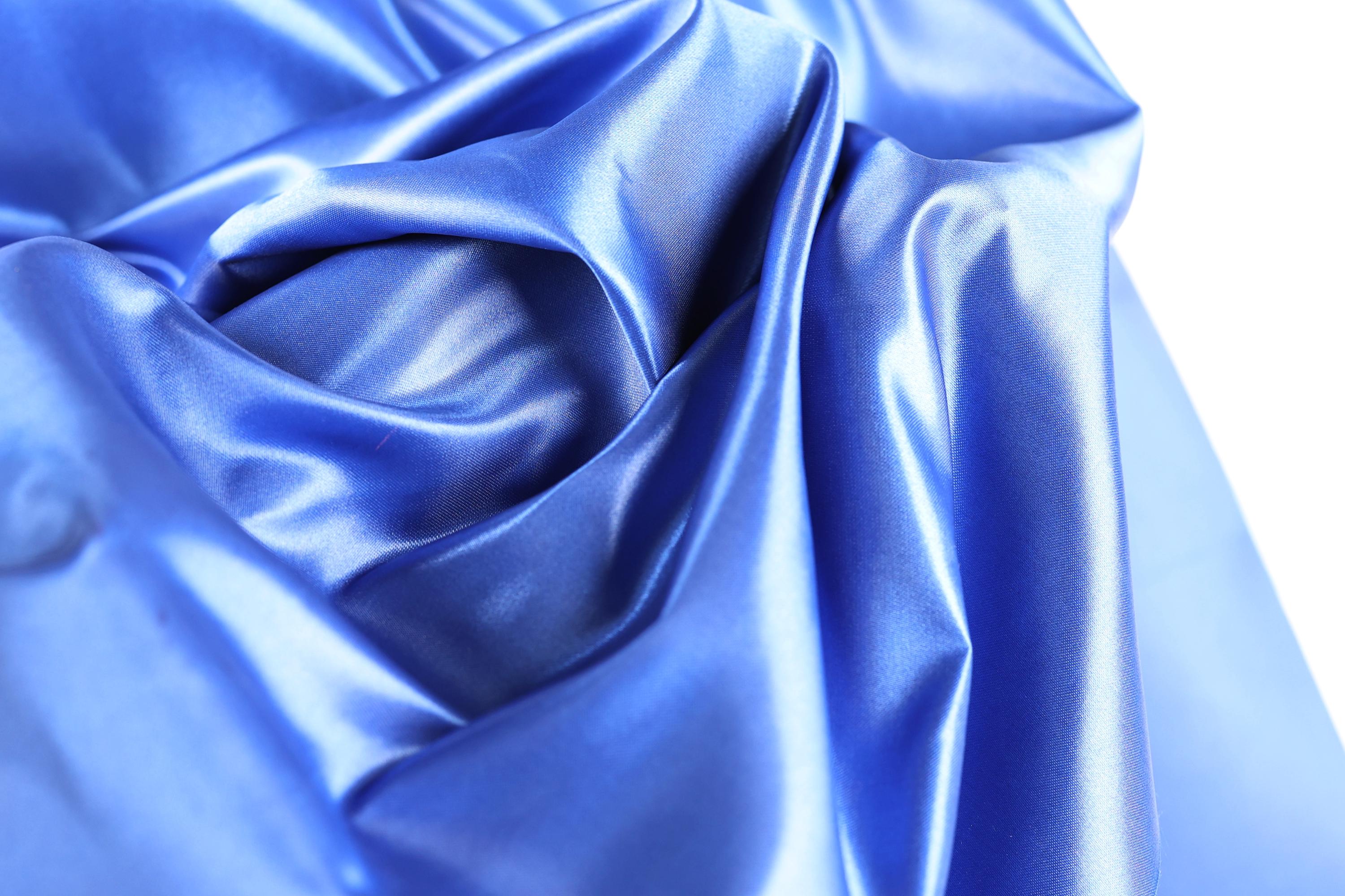 The image is a close-up of a shiny, blue satin fabric.