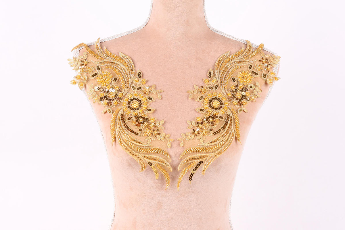 A mannequin with gold and black floral embroidered details on its shoulders.
