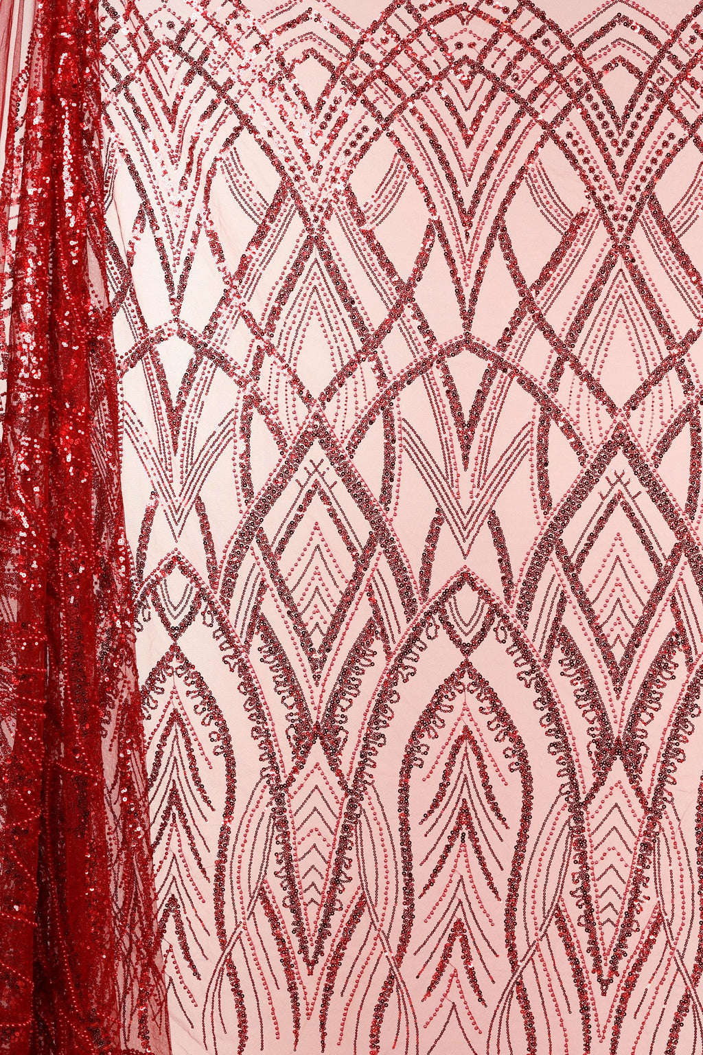 a close-up view of a fabric with a repeating pattern of red sequin designs. The pattern consists of various shapes and lines, creating a visually striking and intricate design. The fabric appears to be a pink background, which contrasts with the red sequin pattern and makes it stand out. The image does not contain any text or other objects, and the focus is solely on the fabric and its design.