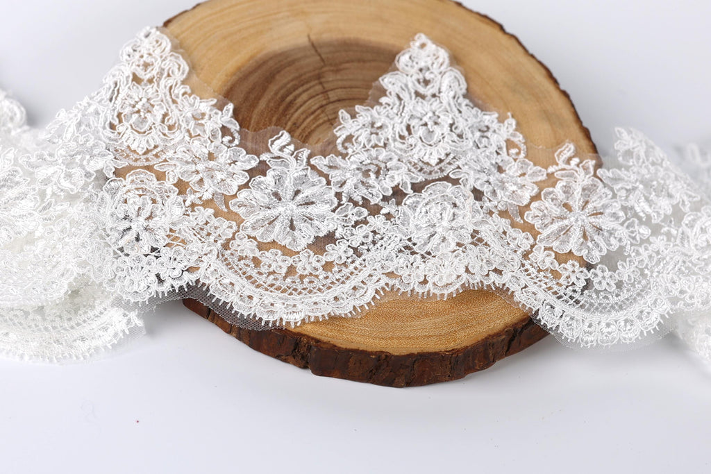 a close-up view of a piece of white lace with intricate floral patterns, placed on a wooden surface.
