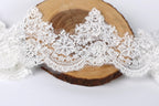 a close-up view of a piece of white lace with intricate floral patterns, placed on a wooden surface.
