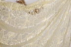 a close-up view of a delicate, sheer fabric with a floral pattern. The fabric appears to be made of a light-colored material, possibly silk or chiffon, and has a delicate, lace-like appearance. The fabric is spread out, revealing its intricate design and texture.