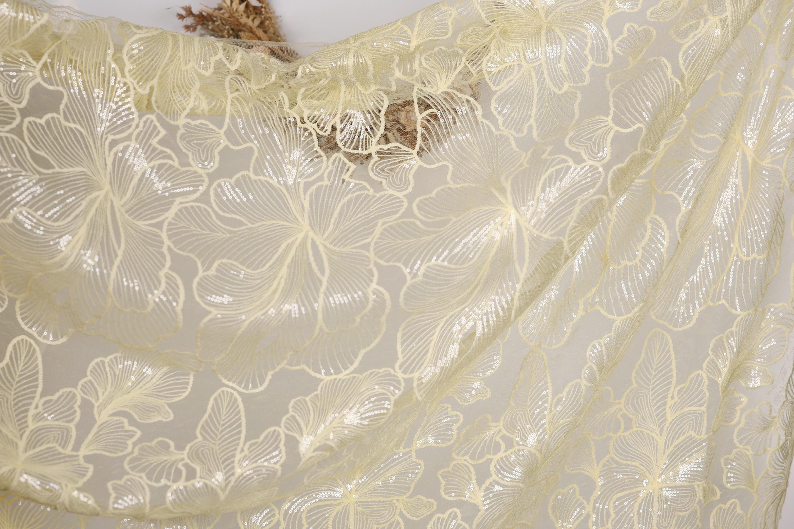a close-up view of a delicate, sheer fabric with a floral pattern. The fabric appears to be made of a light-colored material, possibly silk or chiffon, and has a delicate, lace-like appearance. The fabric is spread out, revealing its intricate design and texture.
