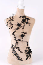 A mannequin with a beige body and black floral designs on its torso and arms.