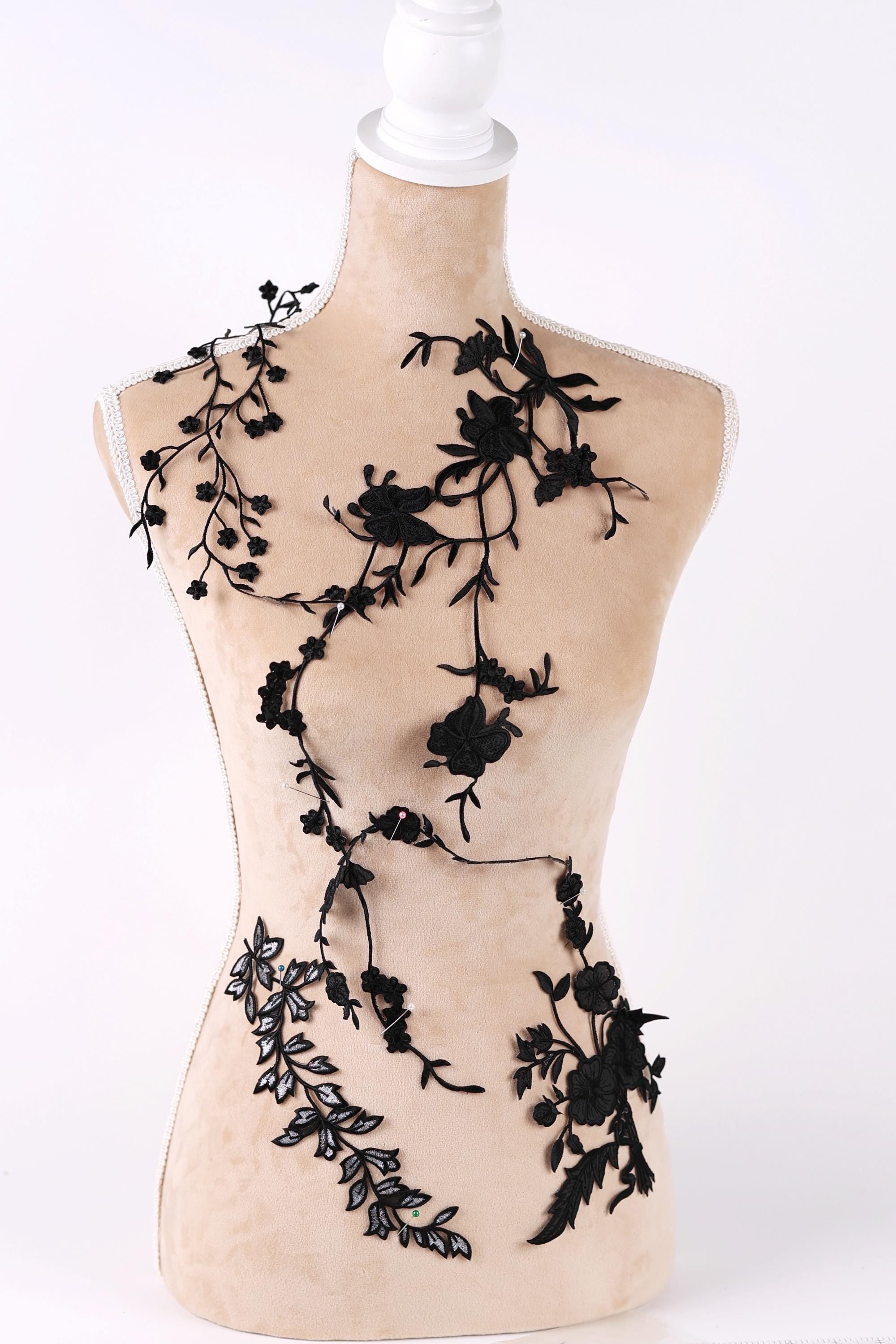 A mannequin with a beige body and black floral designs on its torso and arms.