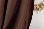 a close-up view of a brown fabric, possibly a curtain or textile, with a blurred background that appears to be a wreath made of dried flowers.
