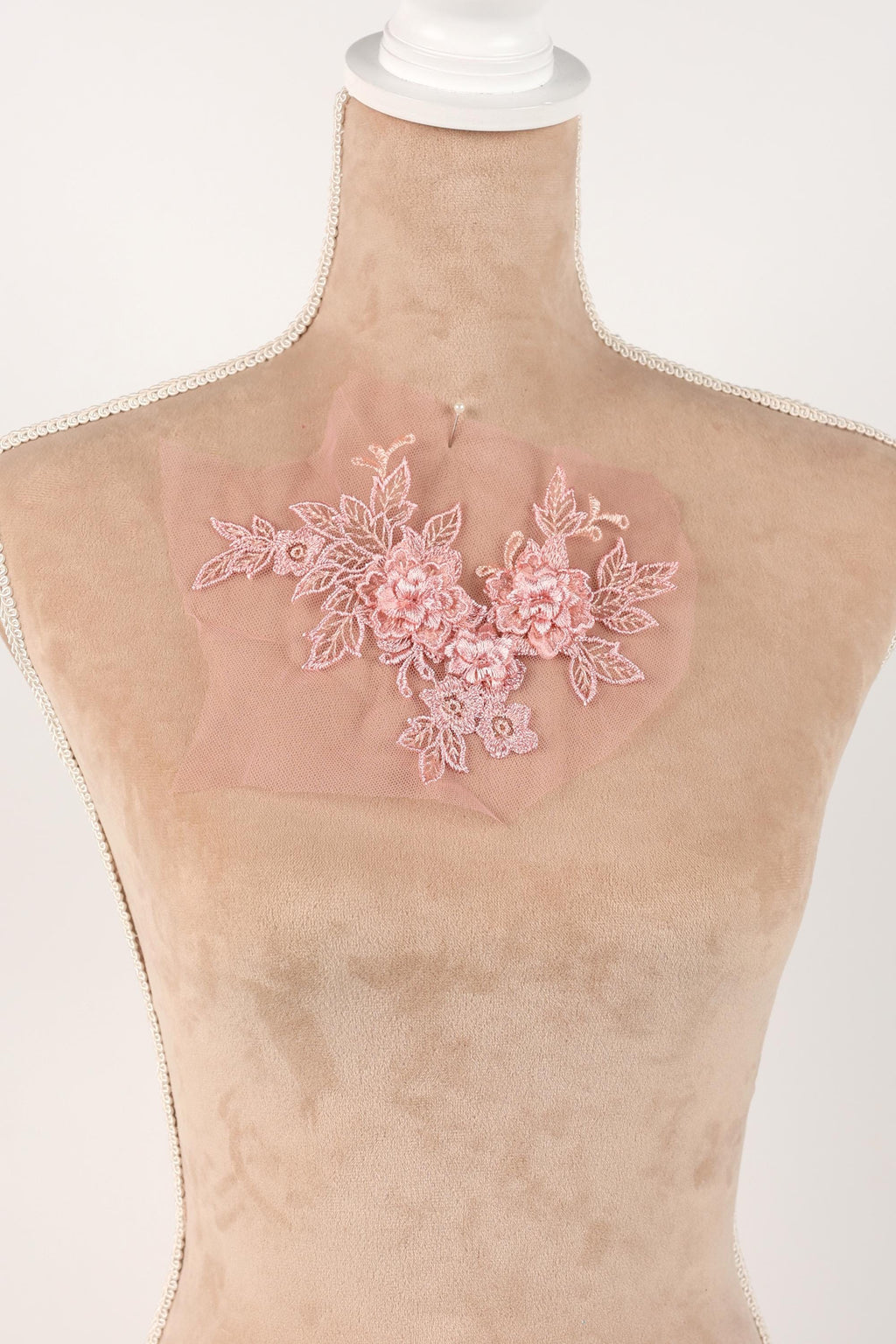 A mannequin wearing a pink floral lace piece on its chest.
