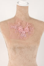 A mannequin wearing a pink floral lace piece on its chest.