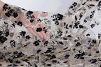 A hand is holding a piece of sheer fabric with a black and white floral pattern.