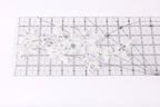 a clear ruler with a floral pattern on it, placed on a white surface.
