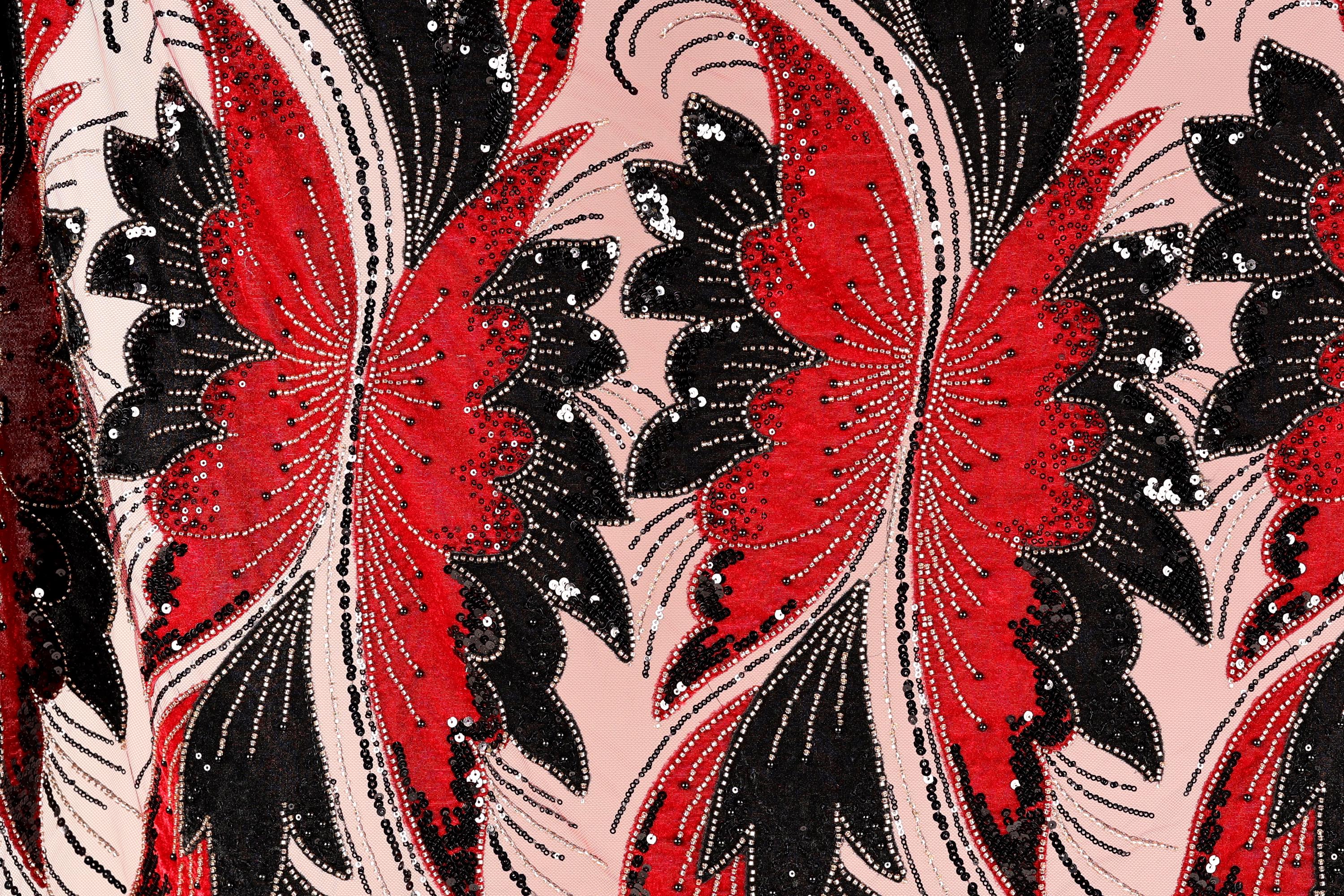 a close-up view of a fabric with a striking pattern of red and black butterflies. The butterflies are intricately designed with black and red sequins, giving the fabric a vibrant and eye-catching appearance. The butterflies are arranged in a repeating pattern, creating a sense of rhythm and movement across the fabric.