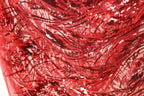 The image is a close-up view of a red fabric with a pattern of sequins and beads, creating a vibrant and eye-catching design.