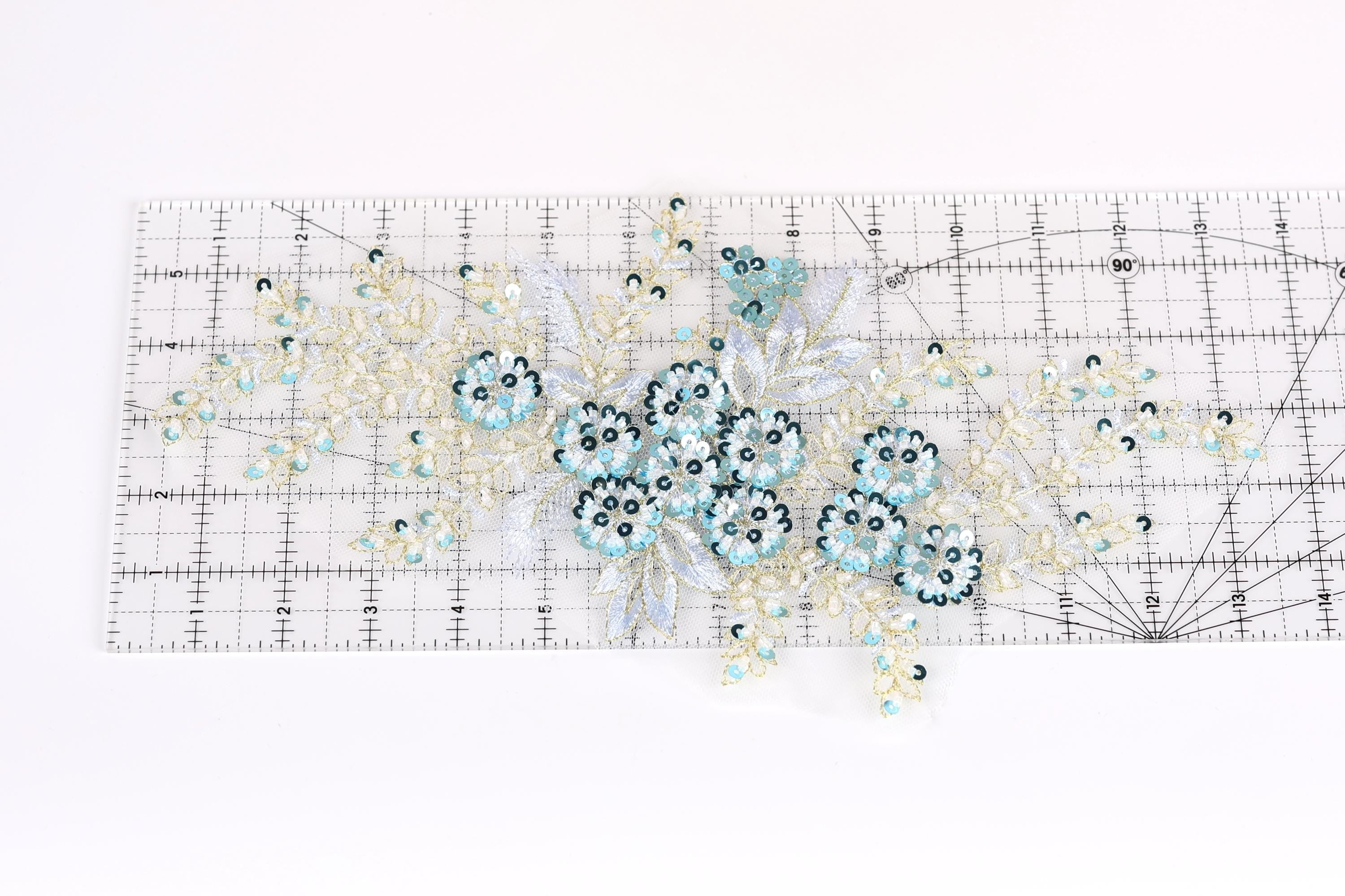 a clear ruler with a floral pattern of blue and white sequins and leaves on it.