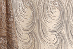a close-up view of a fabric with a repeating pattern of swirls and lines in shades of brown and beige. The pattern appears to be made of sequins or glitter, adding a sparkly and glamorous touch to the fabric.