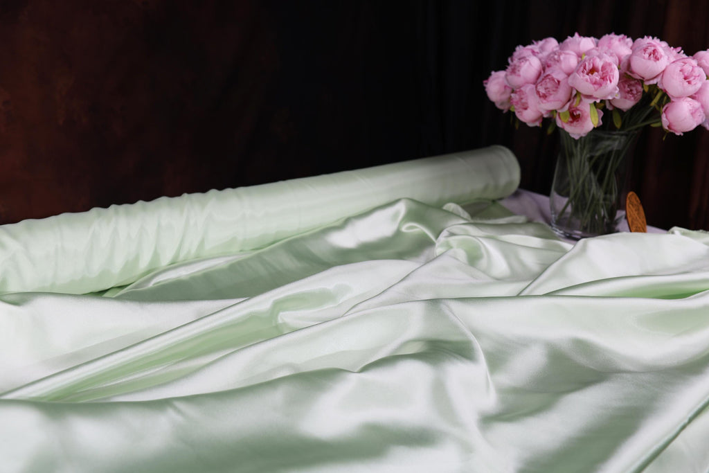 a vase filled with pink flowers sitting on top of a bed