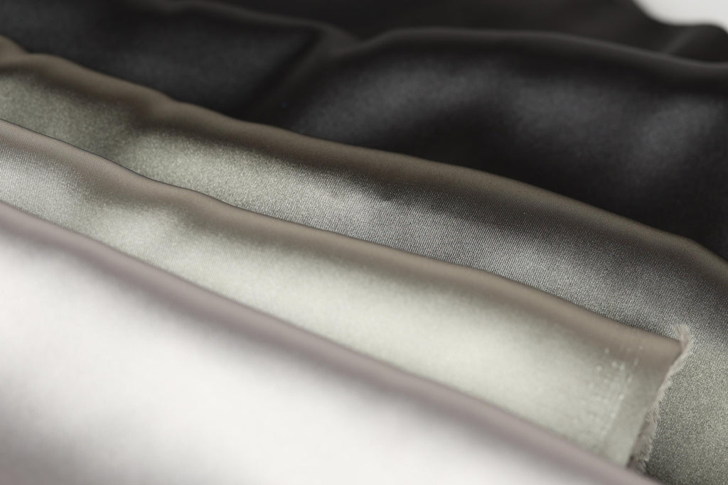 A close-up image of a fabric with a variety of colors, including black, gray, and white, arranged in a layered manner.