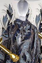 a mannequin wearing a blue and gold patterned cape with gold sequins and a gold metallic design.