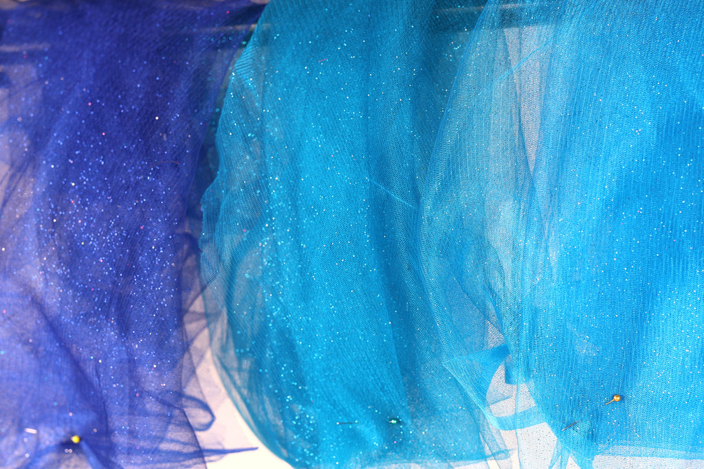a close-up view of a fabric with blue and purple hues, with the blue fabric appearing more vibrant and the purple fabric having a more subtle, glittery appearance.