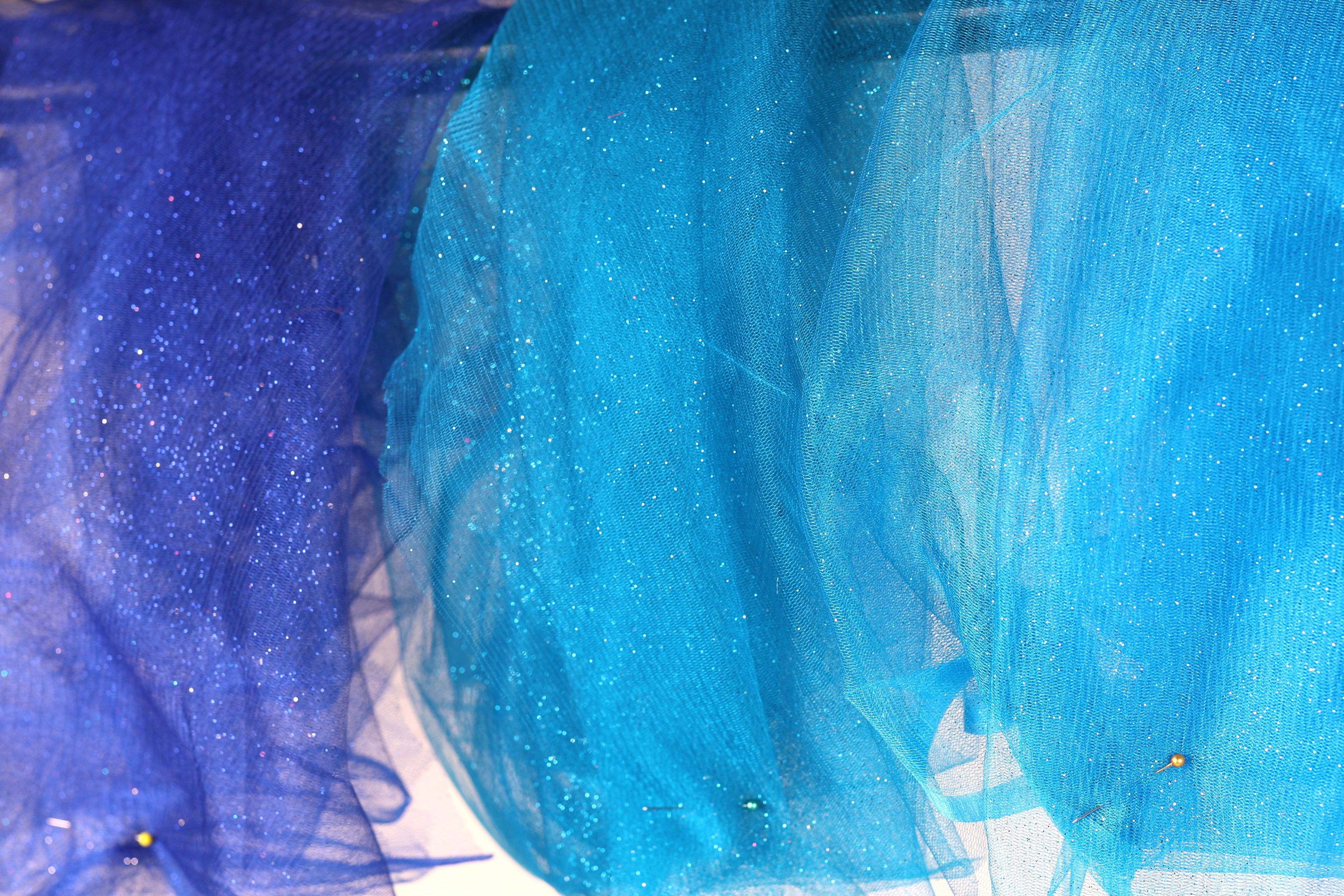 a close-up view of a fabric with blue and purple hues, with the blue fabric appearing more vibrant and the purple fabric having a more subtle, glittery appearance.