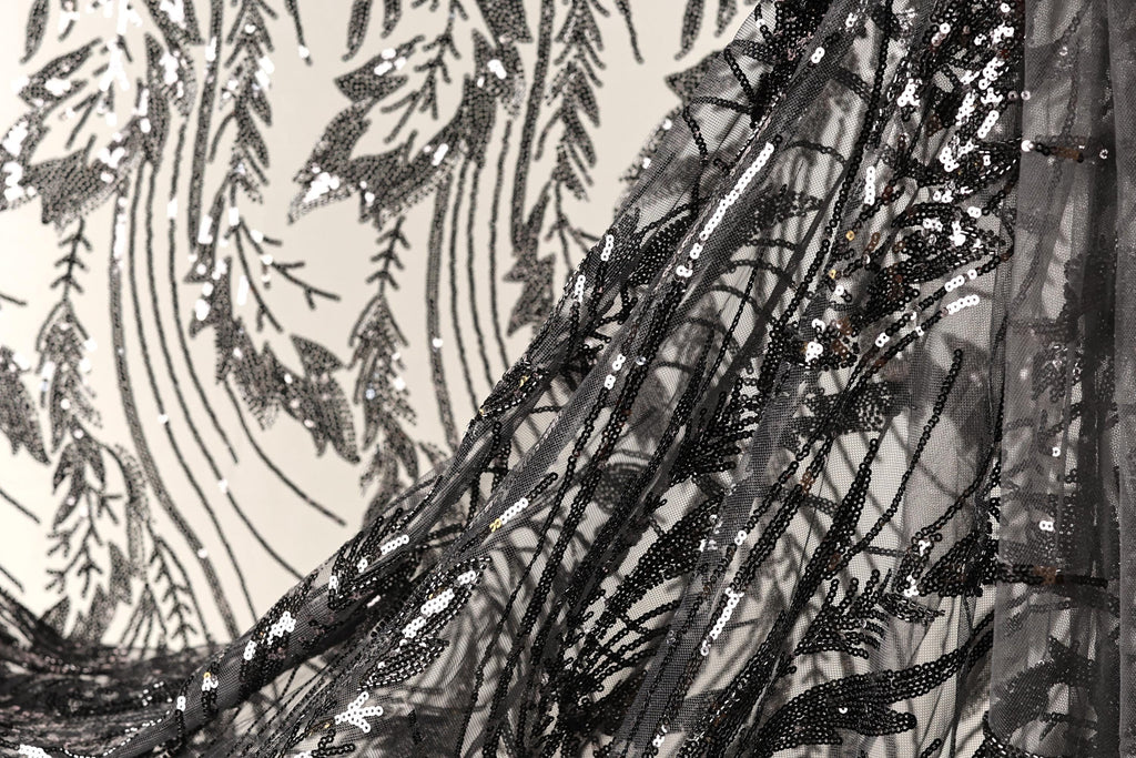 a close-up view of a black and white fabric with intricate black and white sequin patterns. The fabric appears to be a sheer or sheer-like material, with a delicate and elegant design.