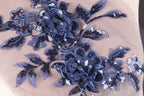 a close-up view of a delicate blue floral embroidery on a light-colored fabric.