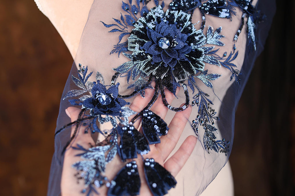 A close-up view of a hand adorned with a delicate blue and black floral embroidery.