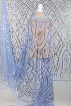 a mannequin wearing a long, flowing blue sequin cape. The cape has a pattern of geometric shapes and lines, creating a visually striking and intricate design. The mannequin is positioned in front of a background with a similar pattern of sequin designs, creating a cohesive and visually appealing display.